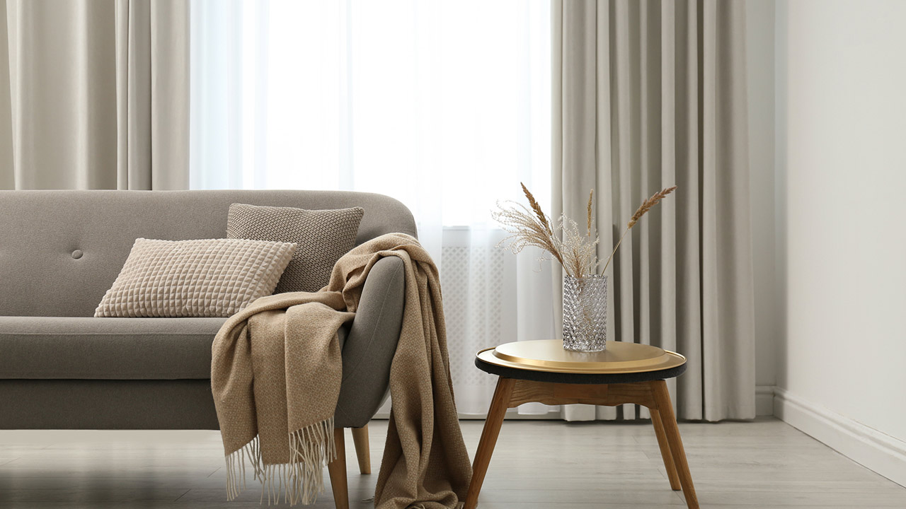 Grey sofa with pillows near window in stylish living room interior