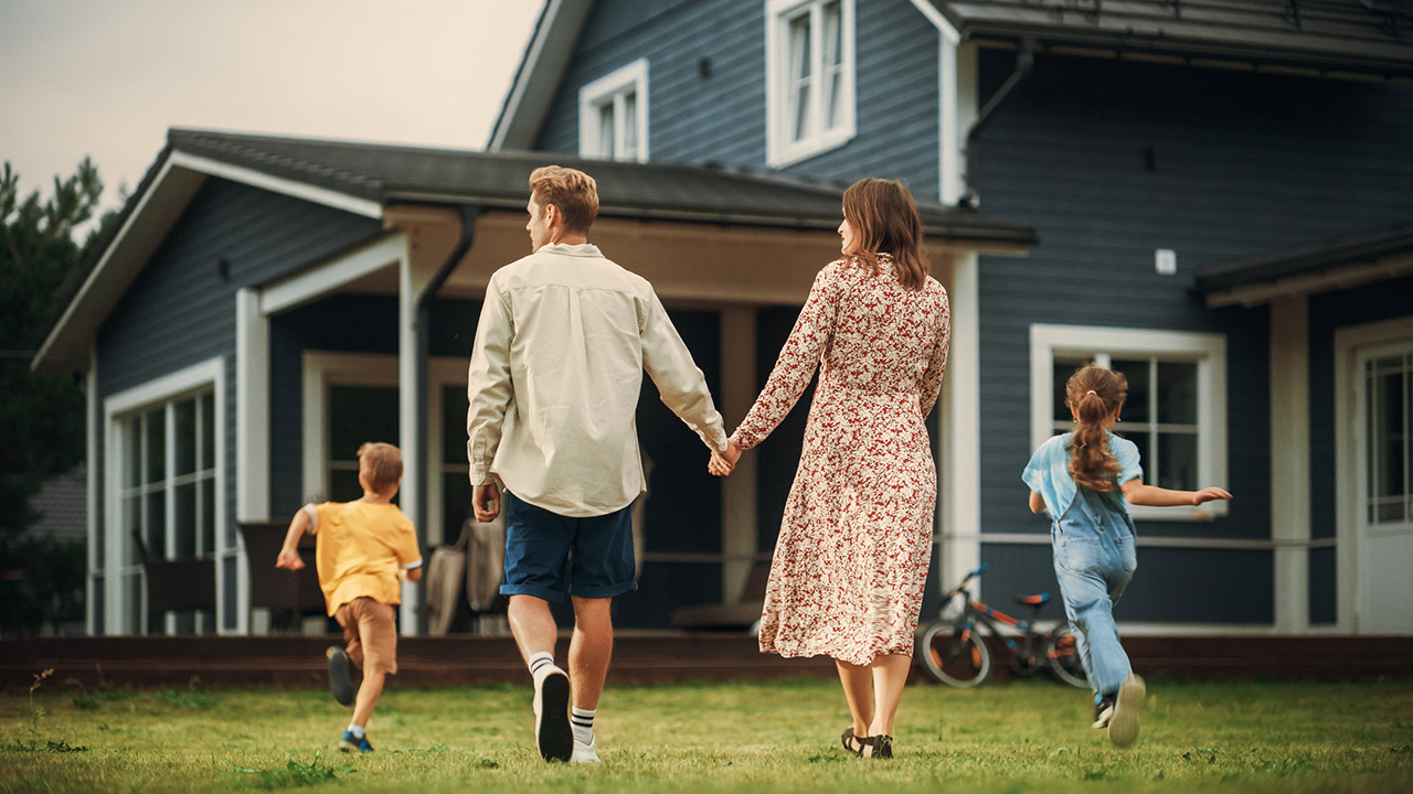 Young couple walking towards a country house with their two children