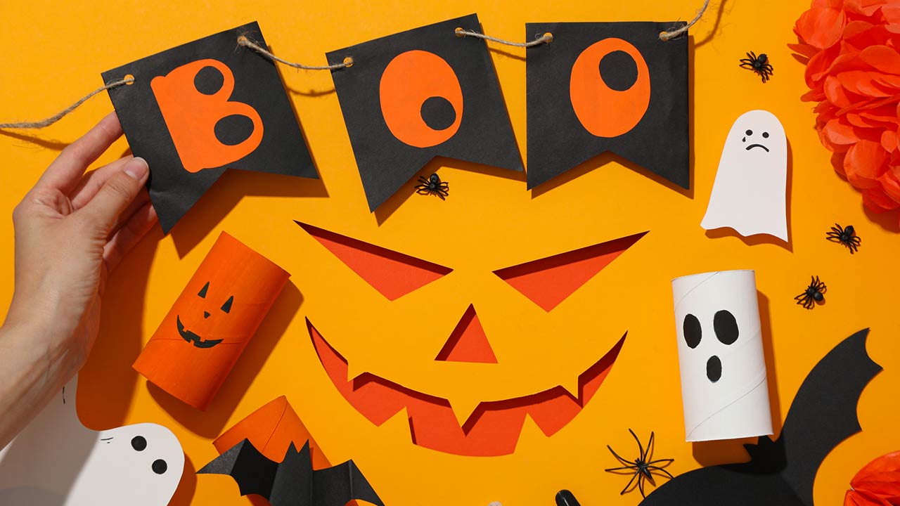 Paper decorations for Halloween on orange background, top view