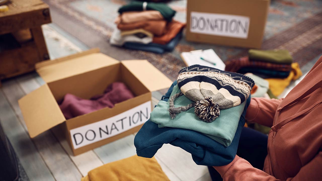 Close-up of woman packing boxes while donating her wardrobe for charity