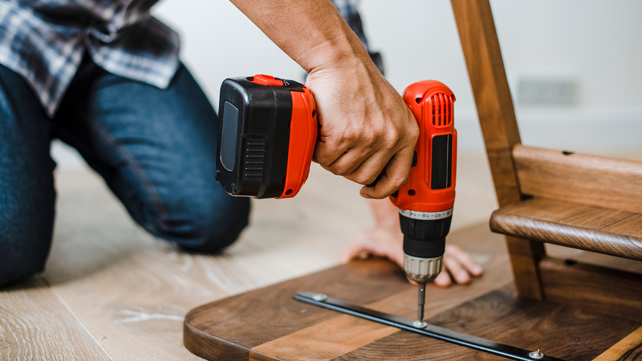 Man using hand drill to assemble a wooden table