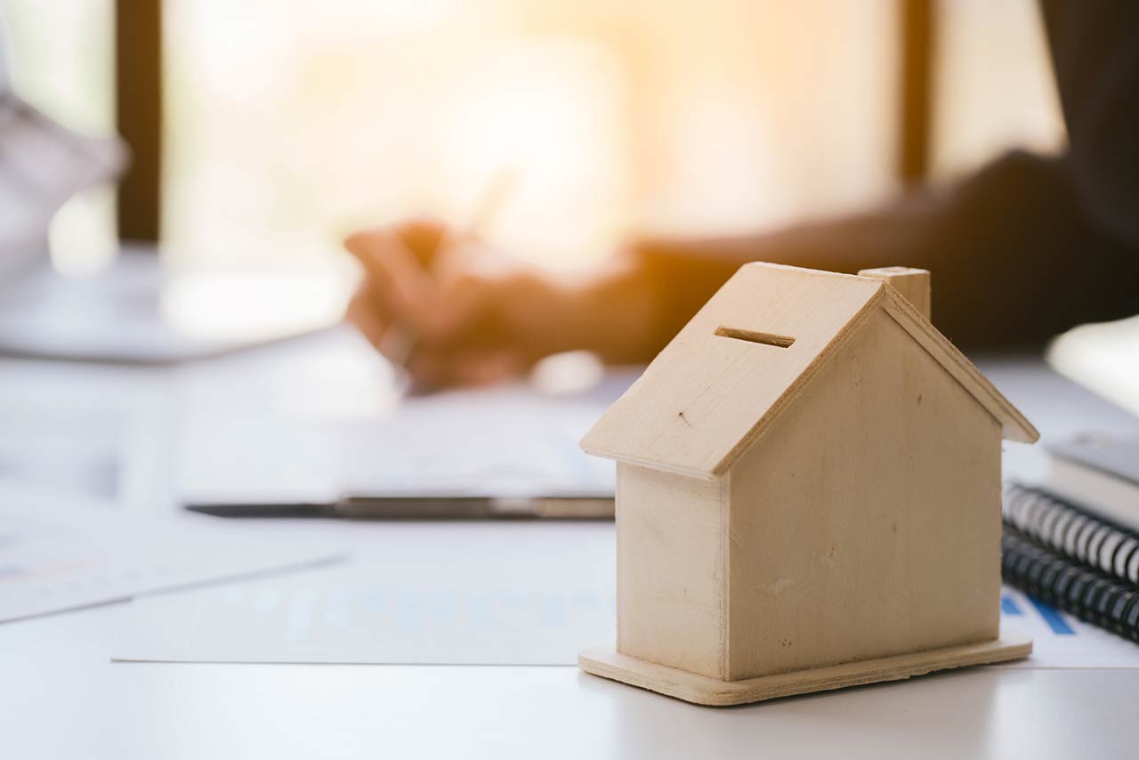 Close up and focus of house model mock up. Blur working hand is holding pen and writing is background
