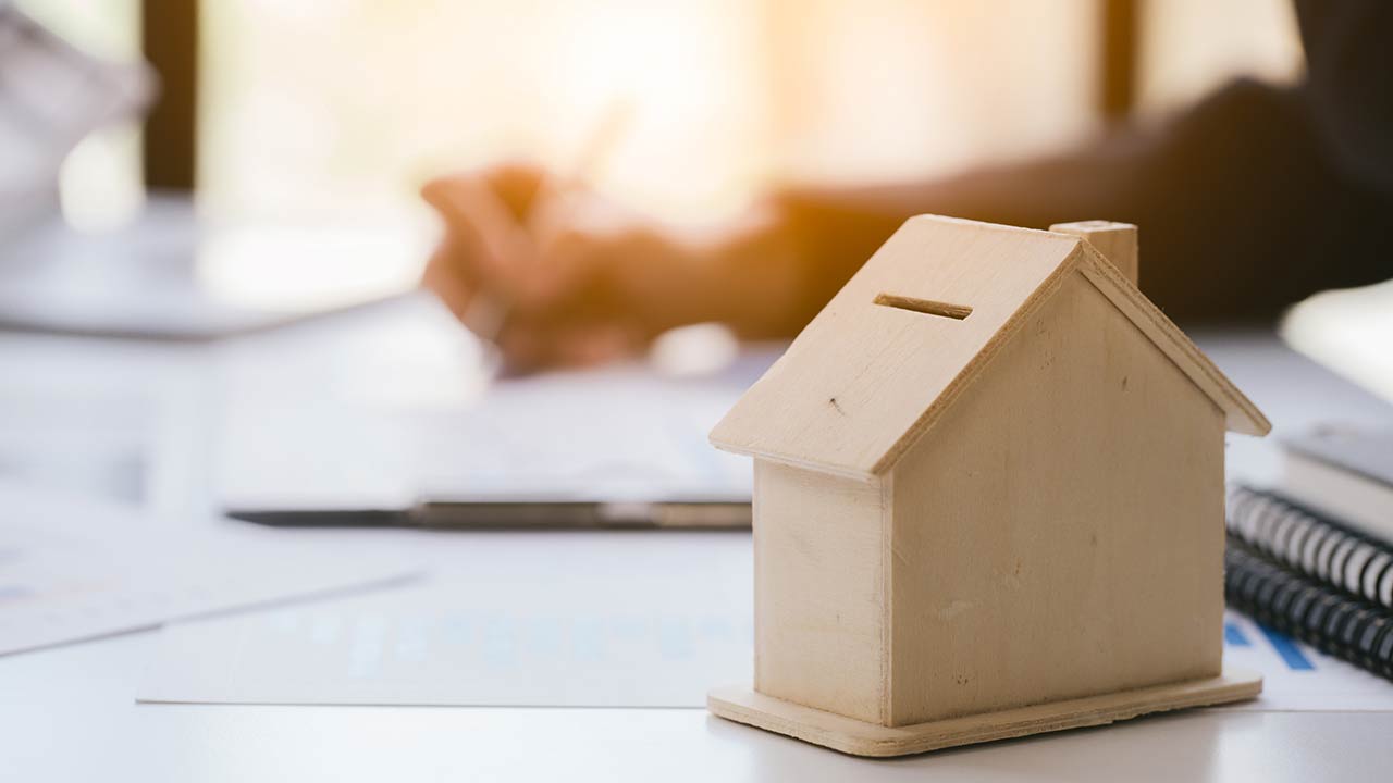 Close up and focus of house model mock up. Blur working hand is holding pen and writing is background