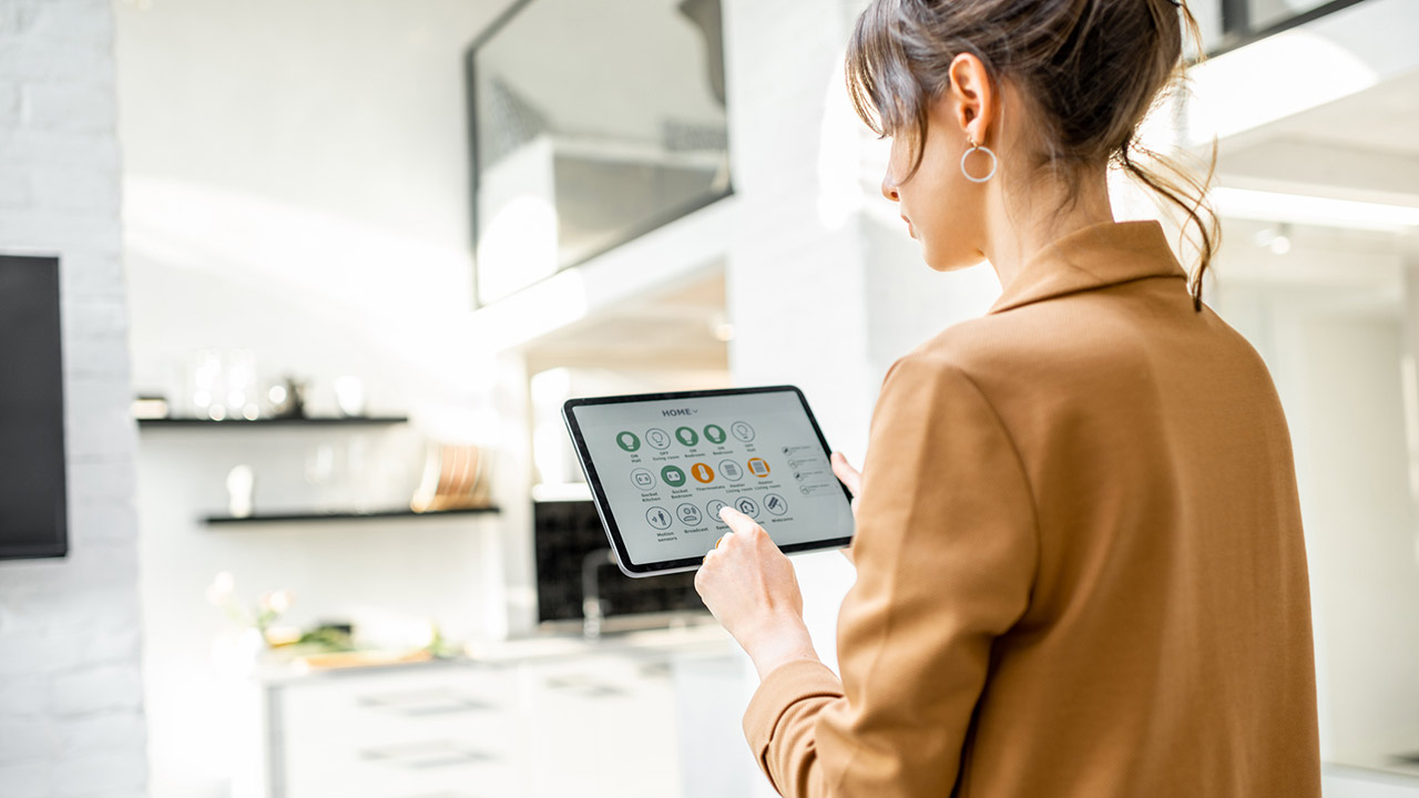 woman controlling smart home devices using a digital tablet with launched application in the white living room